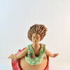 Scultura donna che vola in ceramica con abito rosso, corpetto verde a fiori e coccinella