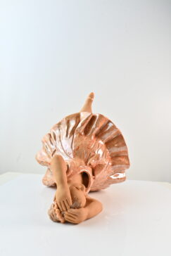 Reclining ceramic dancer sculpture with pink flowing dress and raised leg