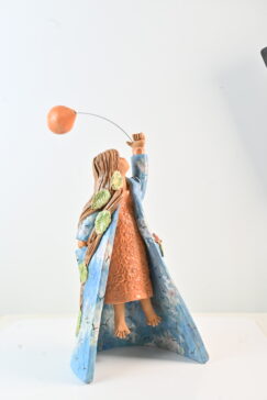 Scultura femminile in ceramica con donna sospesa, mantello azzurro e desiderio