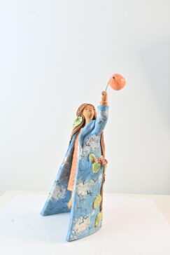 Female ceramic sculpture with long hair, leaves and blue coat